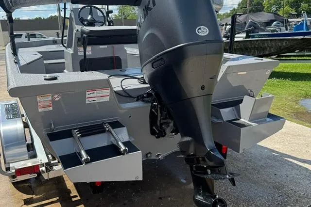 Slide: The Image of 2026 SeaArk Bay Runner 210 boat with outboard motor, parked on a trailer. - 2