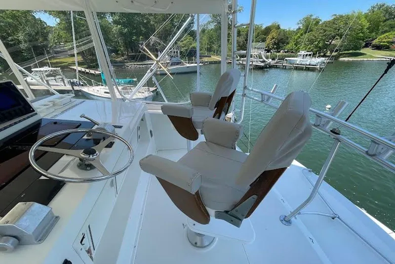 Slide: The Image of 1990 Viking 53 Convertible yacht helm with dual captain chairs and scenic marina view. - 18