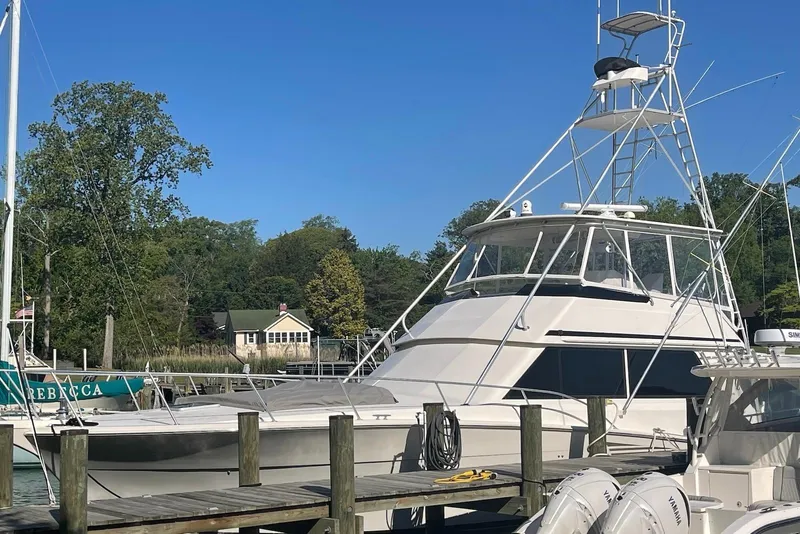 Slide: The Image of 1990 Viking 53 Convertible yacht docked at a marina with clear blue skies. - 2