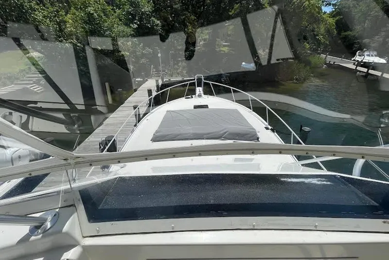 Slide: The Image of View from the helm of a 1990 Viking 53 Convertible yacht docked by a lush shoreline. - 24