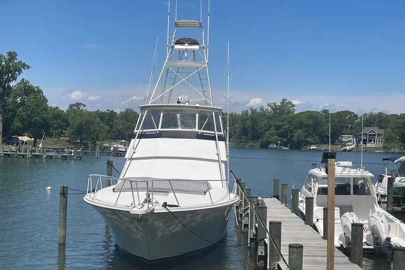 Slide: The Image of 1990 Viking 53 Convertible yacht docked at a serene marina under a clear blue sky. - 3