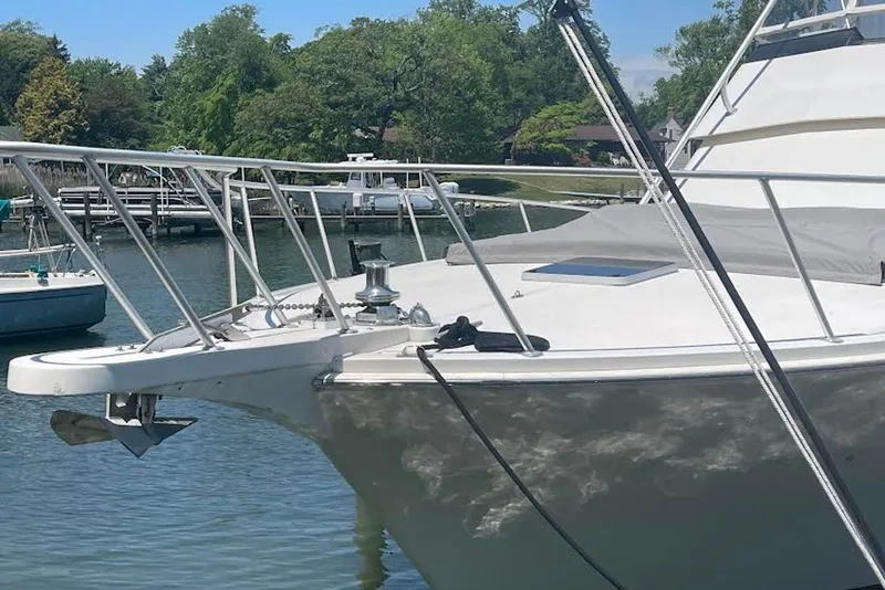 Slide: The Image of 1990 Viking 53 Convertible yacht docked, showcasing sleek design and sturdy bow structure. - 4