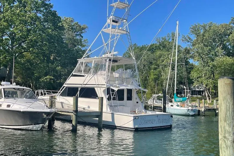 Slide: The Image of 1990 Viking 53 Convertible yacht docked in a serene marina setting. - 6