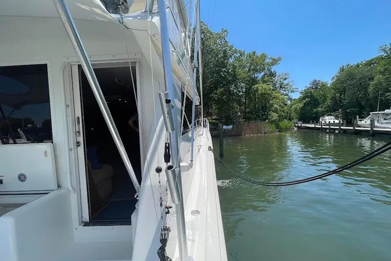 Slide: The Image of 1990 Viking 53 Convertible yacht docked by a serene waterfront with lush greenery. - 9