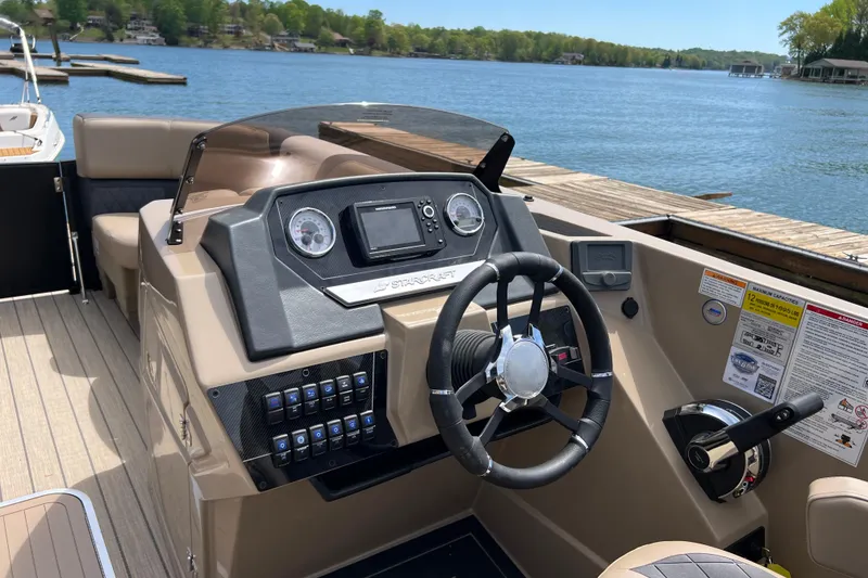 Slide: The Image of 2026 Starcraft SLS 3 R boat dashboard with steering wheel and control panel by a lake. - 8