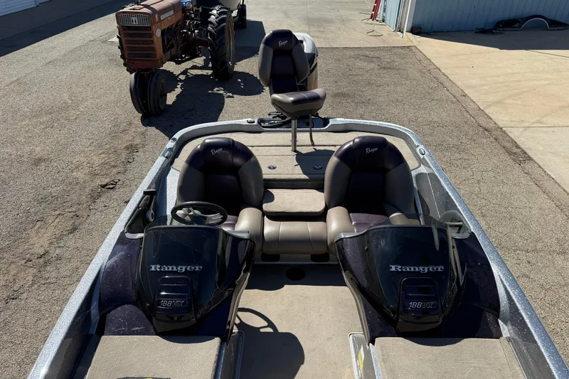 Slide: The Image of 2009 Ranger 188 VX boat with dual consoles, parked near a vintage tractor. - 15