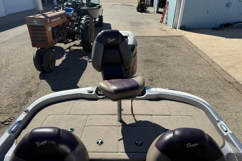 Slide: The Image of 2009 Ranger 188 VX boat with seats, parked near a vintage tractor. - 24