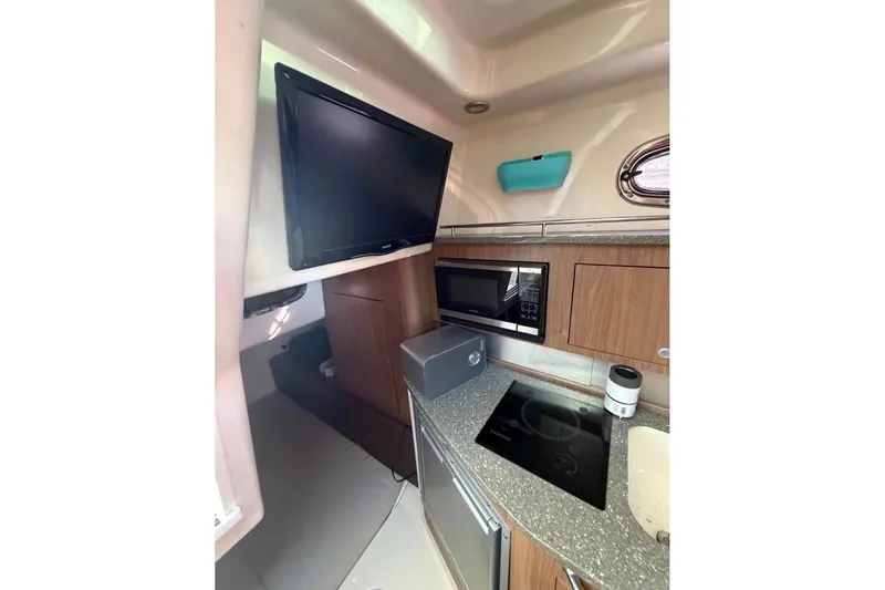 Slide: The Image of Interior of 2018 Boston Whaler 315 Conquest featuring kitchen amenities and a mounted TV. - 15