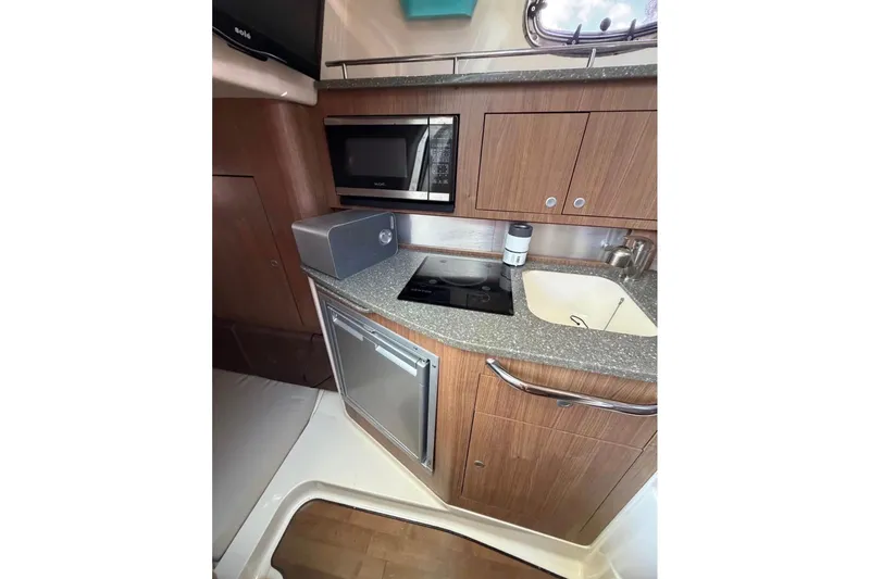 Slide: The Image of 2018 Boston Whaler 315 Conquest galley with microwave, sink, and compact refrigerator. - 17
