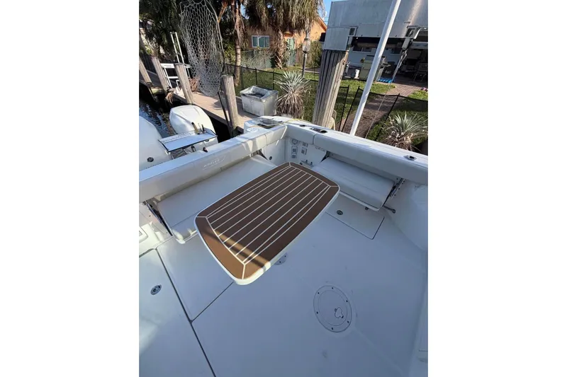 Slide: The Image of 2018 Boston Whaler 315 Conquest boat deck with seating and table, docked near waterfront homes. - 5