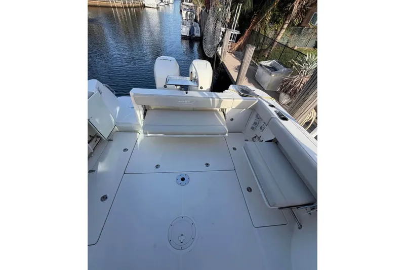Slide: The Image of 2018 Boston Whaler 315 Conquest boat deck with seating, docked by water. - 6