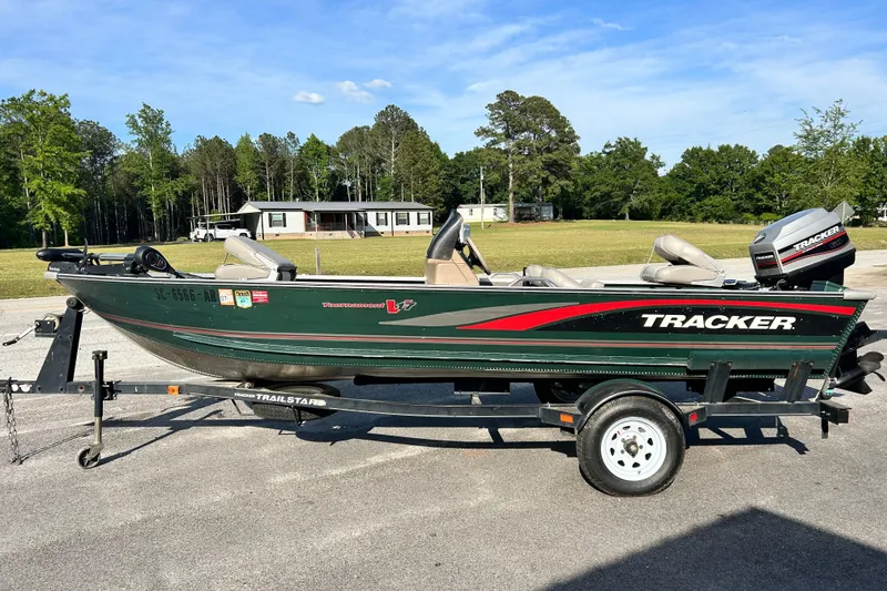 The Image of 1996 Tracker Tournament V-17 fishing boat on trailer, parked outdoors. - 0