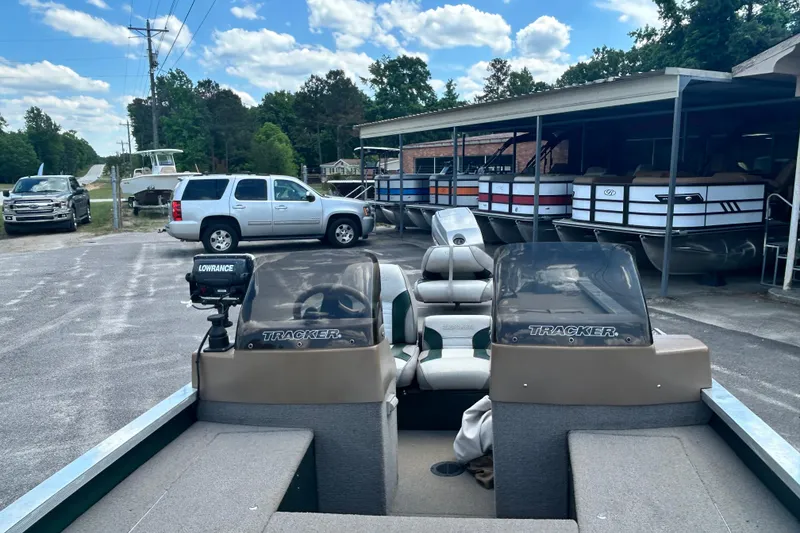 Slide: The Image of 1996 Tracker Tournament V-17 boat parked near SUVs and other boats under a clear sky. - 10