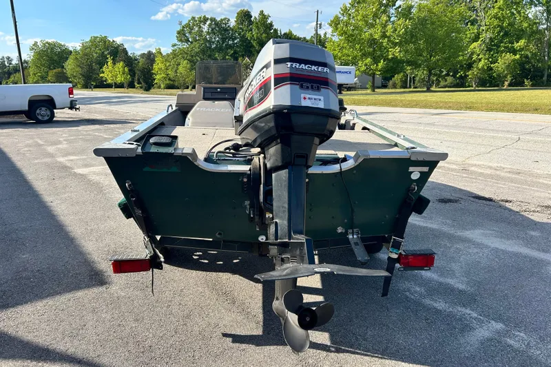 Slide: The Image of 1996 Tracker Tournament V-17 boat with outboard motor, parked outdoors on a sunny day. - 17