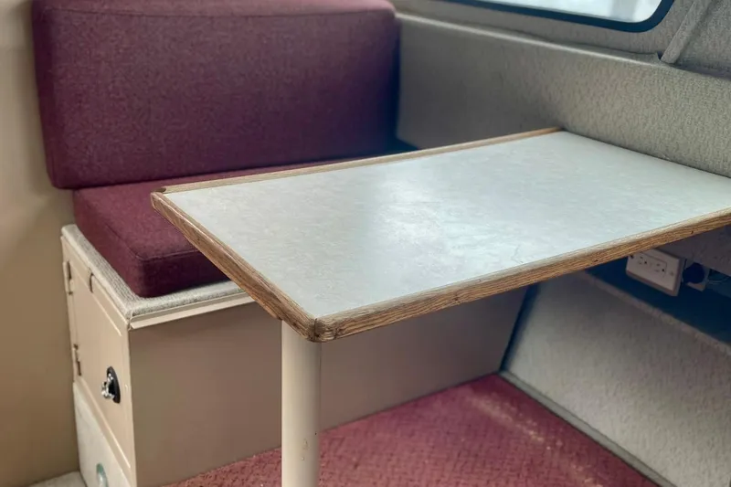 Slide: The Image of Interior of a 2005 Lifetimer 3540 with a table and maroon seating. - 9