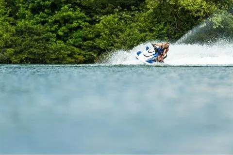 Slide: The Image of 2021 Yamaha WaveRunner FX Cruiser HO speeding on a lake with lush green background. - 16