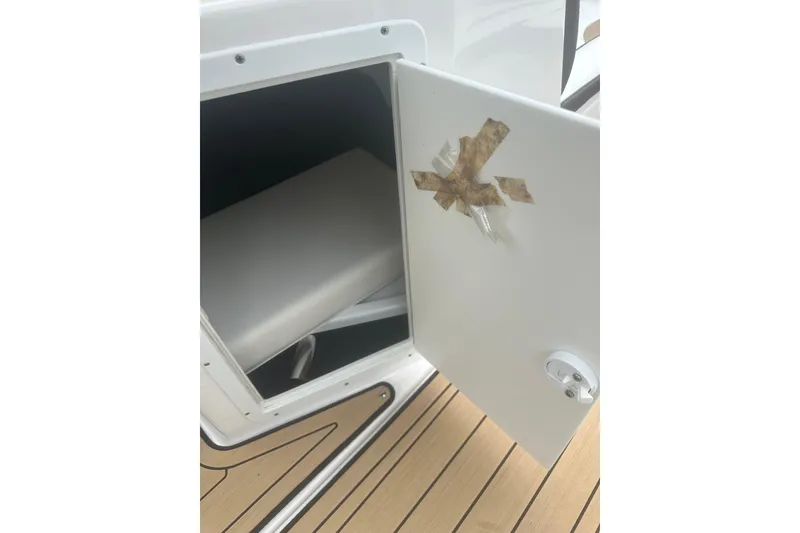 Slide: The Image of Open storage compartment on 2021 Yamaha Boats 195S with taped door, revealing interior. - 16