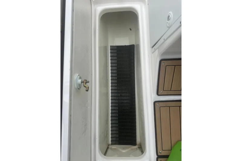 Slide: The Image of Storage compartment in a 2021 Yamaha Boats 195S, featuring a black mat and wooden flooring. - 17