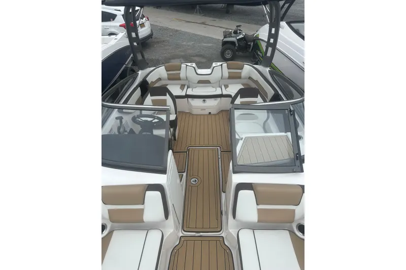 Slide: The Image of 2021 Yamaha Boats 195S interior with tan and white seating, sleek design, and spacious layout. - 18