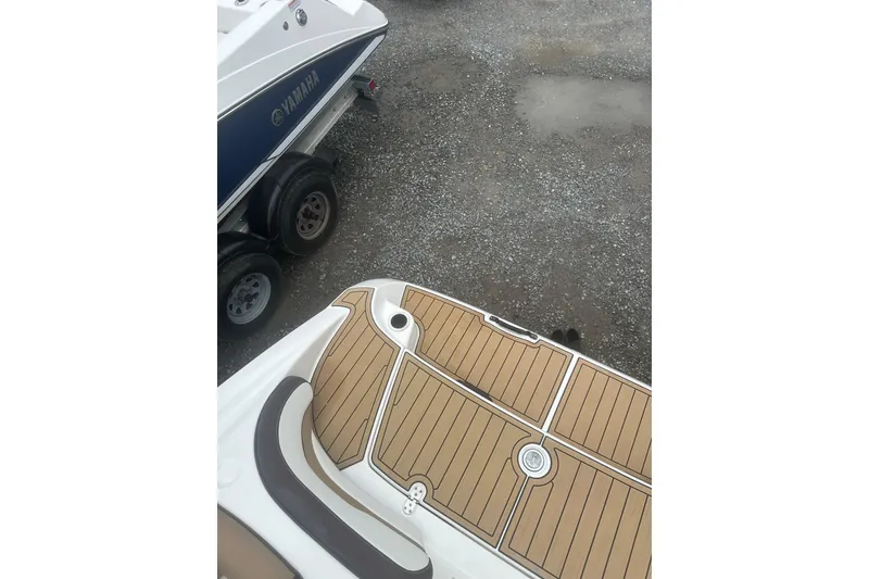 Slide: The Image of 2021 Yamaha Boats 195S with teak-style deck, parked on gravel. - 19