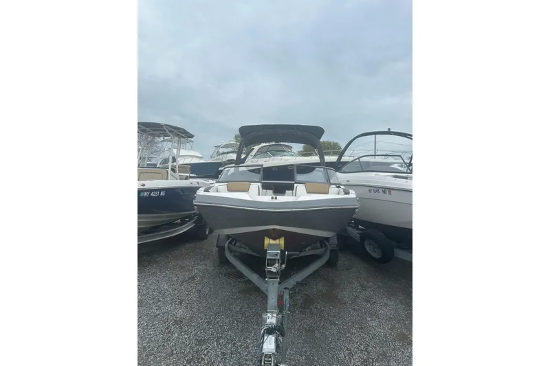 Slide: The Image of 2021 Yamaha Boats 195S on trailer, parked among other boats, under cloudy sky. - 2