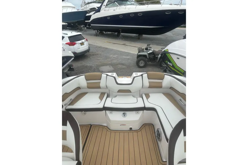 Slide: The Image of 2021 Yamaha Boats 195S interior with white and tan seating, docked near other boats. - 22