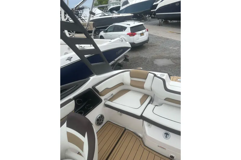 Slide: The Image of 2021 Yamaha Boats 195S interior with white and tan seating, docked near other boats. - 25