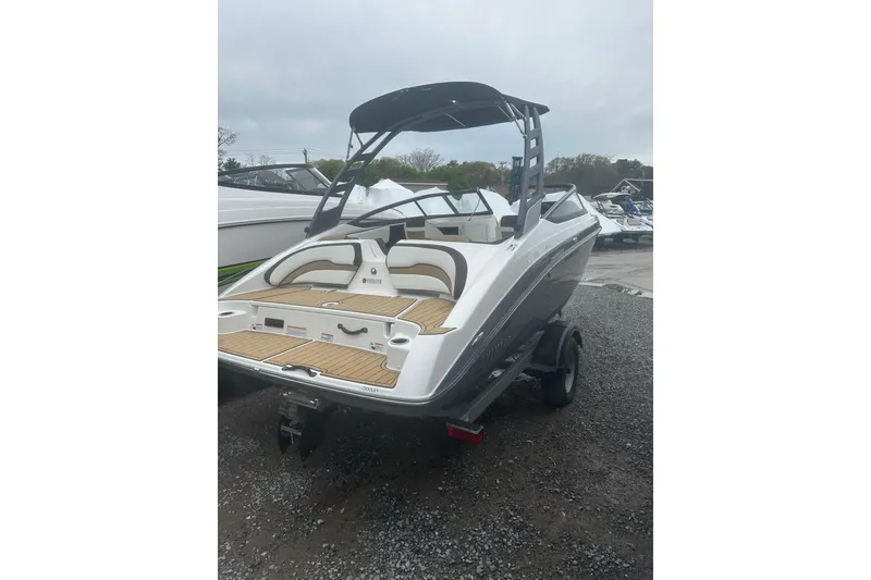 Slide: The Image of 2021 Yamaha Boats 195S, sleek design, rear view, parked on gravel, overcast sky. - 7