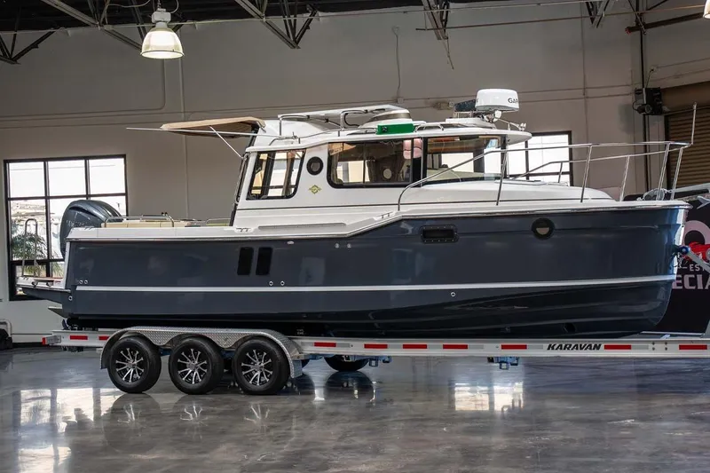 The Image of 2025 Ranger Tugs R-25 boat on a trailer in a showroom setting. - 1