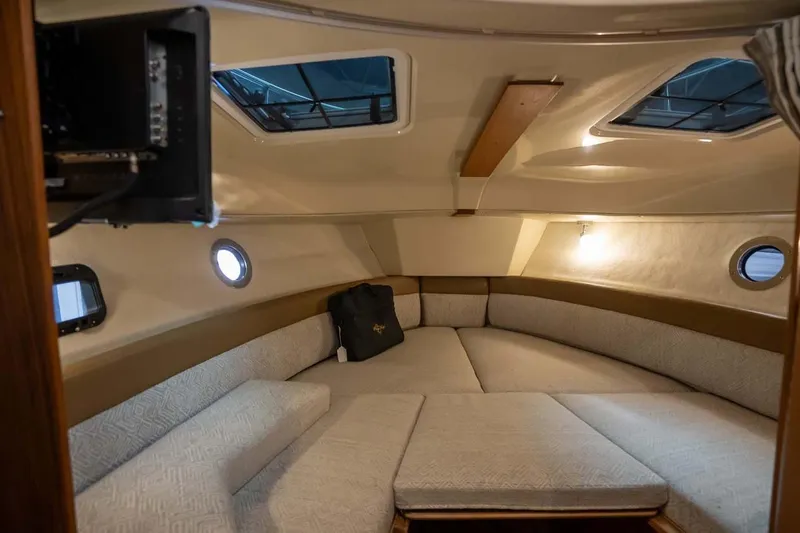 Slide: The Image of Interior cabin of 2025 Ranger Tugs R-25, featuring cozy seating and porthole windows. - 11
