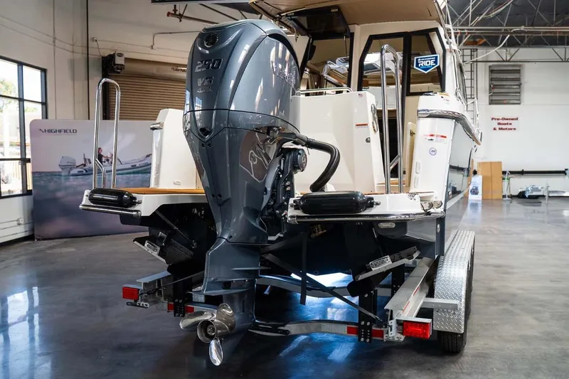 Slide: The Image of 2025 Ranger Tugs R-25 boat with powerful outboard motor in a showroom. - 5