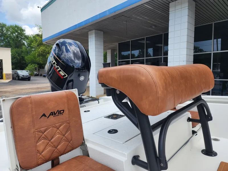 Slide: The Image of Avid 19 FSX 2026 boat with brown leather seats and outboard motor. - 15