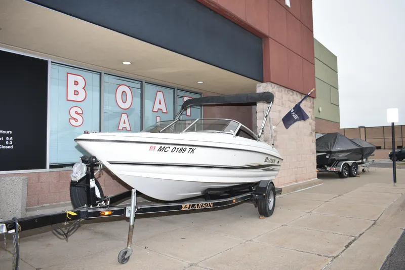 Slide: The Image of 2004 Larson SEi 180 boat on trailer outside a boat sale store. - 2