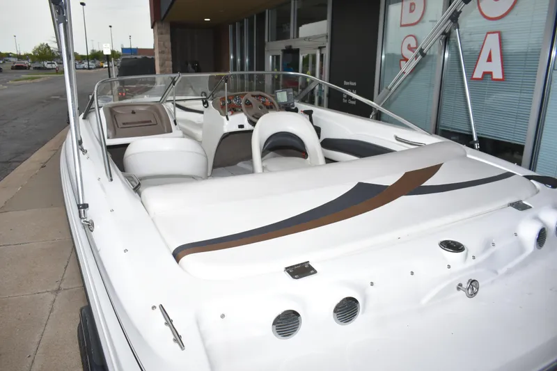 Slide: The Image of 2004 Larson SEi 180 boat with white interior, docked near a building entrance. - 4