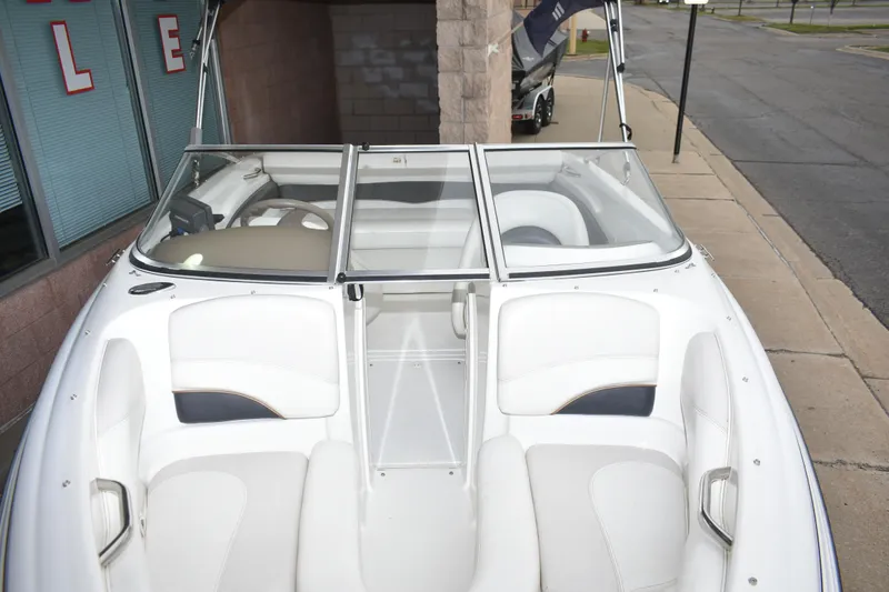 Slide: The Image of 2004 Larson SEi 180 boat with white interior, parked on a street near a building. - 7