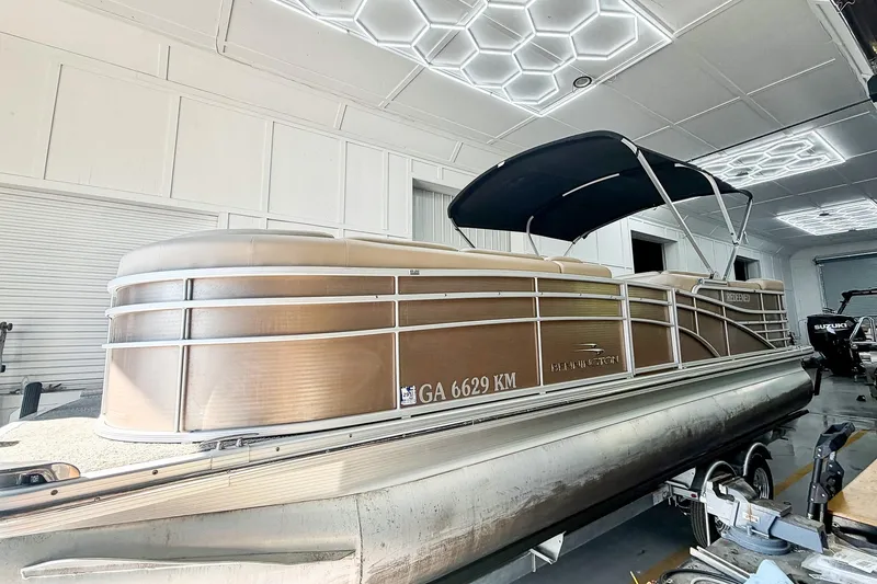 The Image of 2011 Bennington 2275RLi pontoon boat with canopy in a modern garage setting. - 0