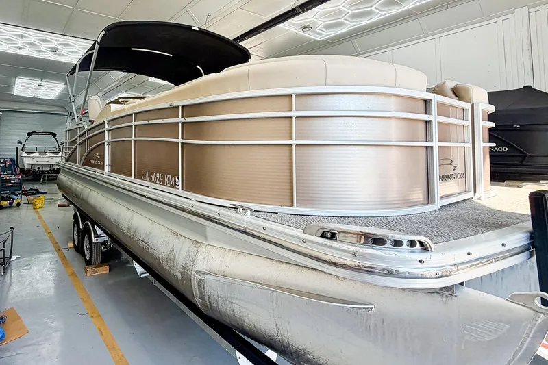 Slide: The Image of 2011 Bennington 2275RLi pontoon boat in a garage, showcasing sleek design and spacious seating. - 2
