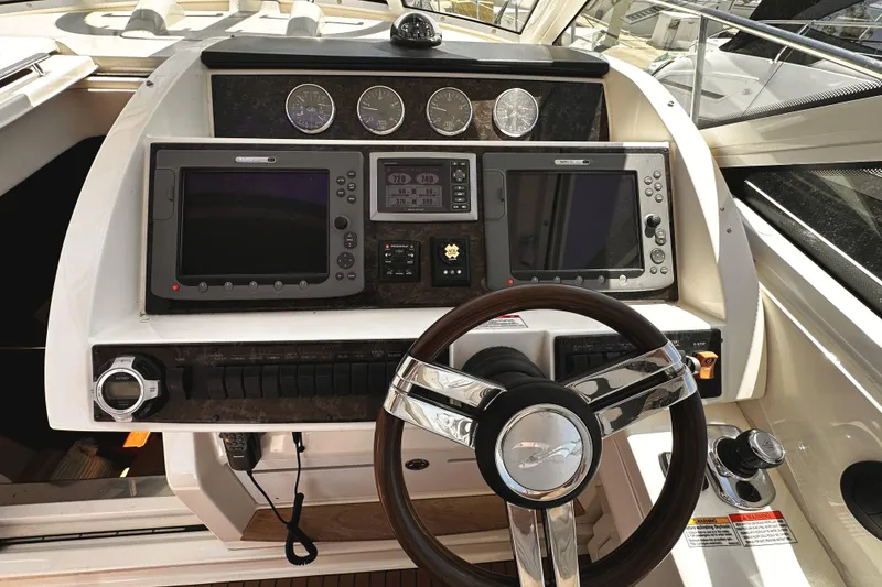 Slide: The Image of Cockpit of 2010 Sea Ray 450 Sundancer with navigation screens and steering wheel. - 27
