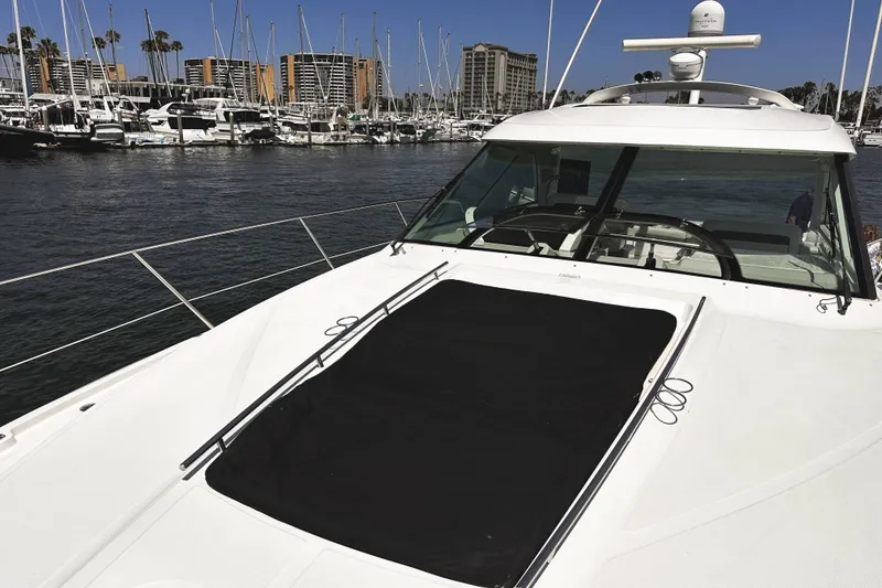 Slide: The Image of 2010 Sea Ray 450 Sundancer yacht docked in a marina with cityscape background. - 49