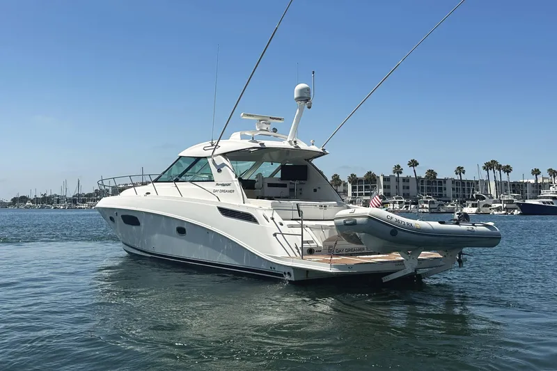 Slide: The Image of 2010 Sea Ray 450 Sundancer yacht on calm water, with marina and palm trees in background. - 6