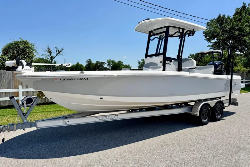 The Image of 2021 Robalo 246 Cayman boat on trailer, parked on a sunny street. - 1