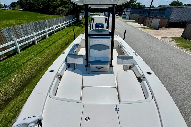 Slide: The Image of 2021 Robalo 246 Cayman boat with spacious deck and seating, parked on a sunny street. - 15