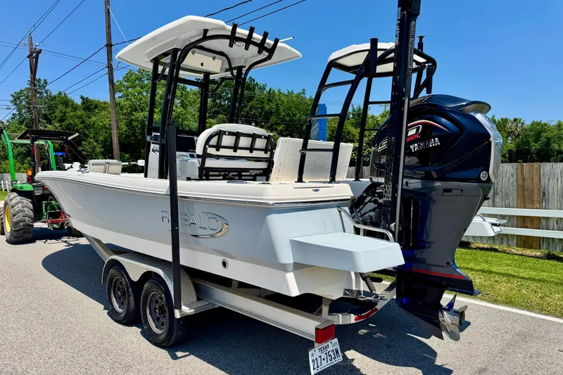 Slide: The Image of 2021 Robalo 246 Cayman boat on trailer with Yamaha engine, parked outdoors. - 2