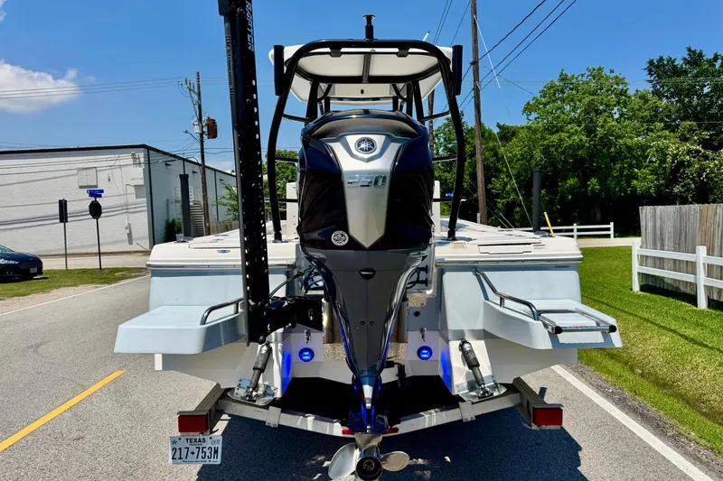 Slide: The Image of 2021 Robalo 246 Cayman boat on trailer, featuring powerful outboard motor, parked on sunny street. - 3