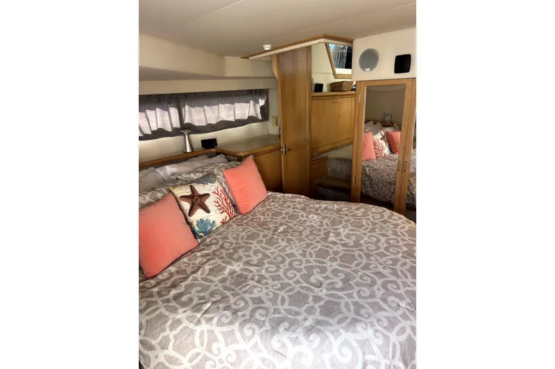 Slide: The Image of Cozy bedroom interior of 1997 Carver 430 Cockpit Motor Yacht with decorative pillows and wood accents. - 23