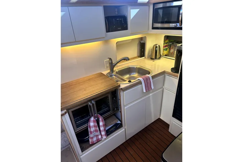 Slide: The Image of Compact kitchen area in a 1997 Carver 430 Cockpit Motor Yacht with modern appliances. Stove and oven has been removed and replaced with an electric oven and a portable cooktop. - 4