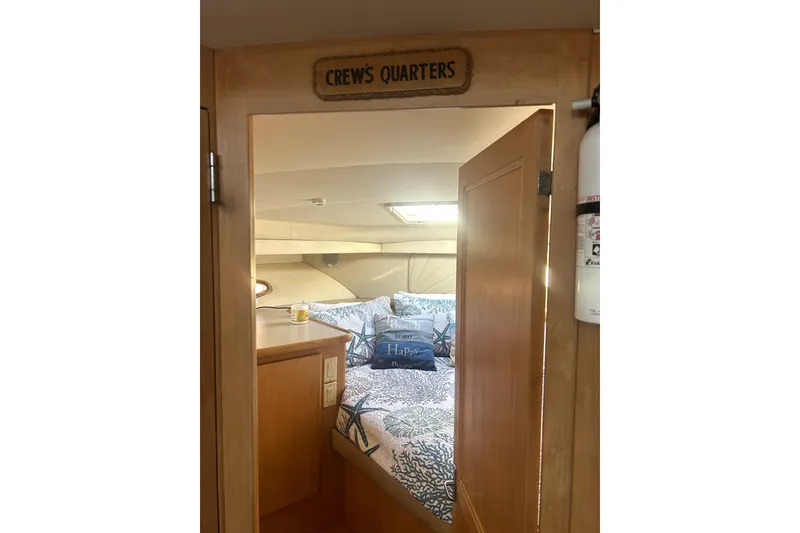 Slide: The Image of Crew's quarters in 1997 Carver 430 Cockpit Motor Yacht, featuring cozy bedding and wooden interior. - 6