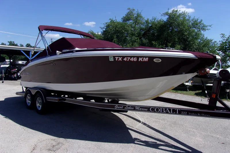 The Image of 2007 Cobalt 222 boat on trailer, maroon cover, parked outdoors. - 1