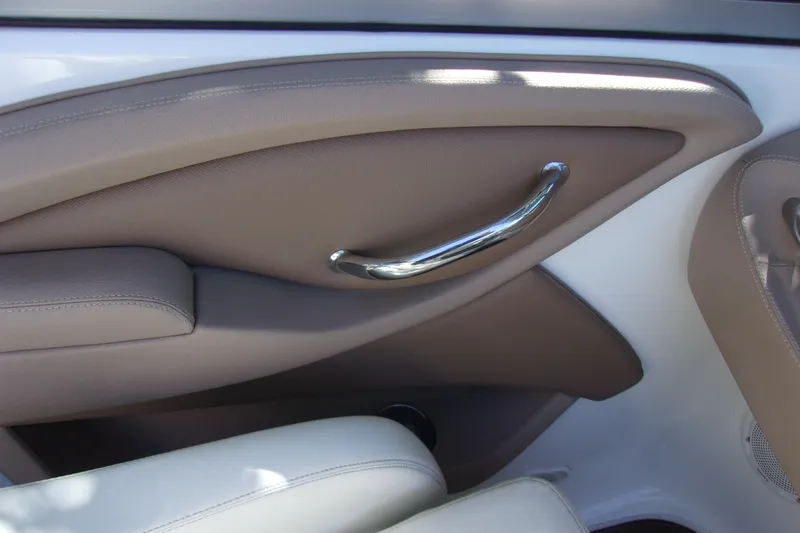 Slide: The Image of Interior detail of a 2007 Cobalt 222 boat, featuring beige upholstery and chrome handle. - 10