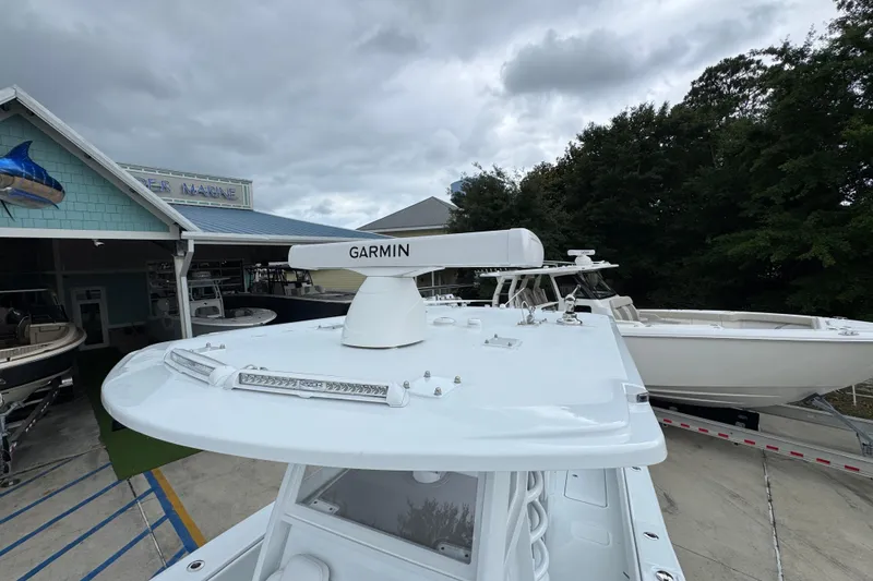 Slide: The Image of 2026 Invincible 33 Open Fisherman boat with Garmin radar, docked near a marine shop. - 23
